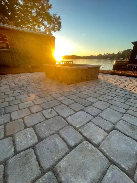 Paver patio and fire pit facing the lake at sunset