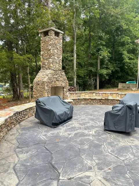 Fieldstone chimney and seating wall around a stamped concrete patio