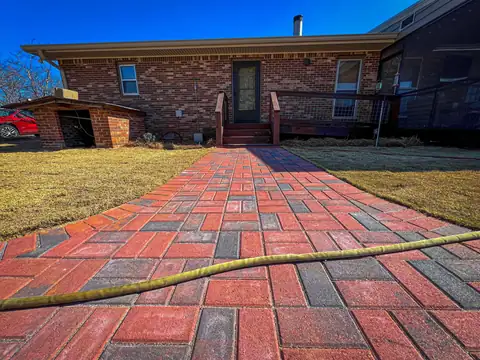 Red and charcoal clay paver walkway leading to a brick house