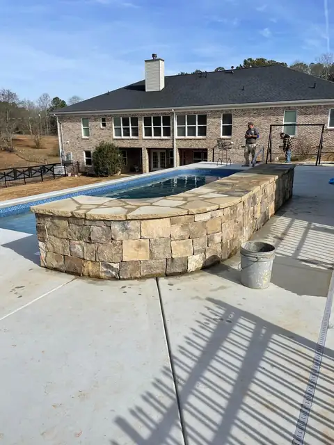 Curved stacked stone wall along the edge of a pool